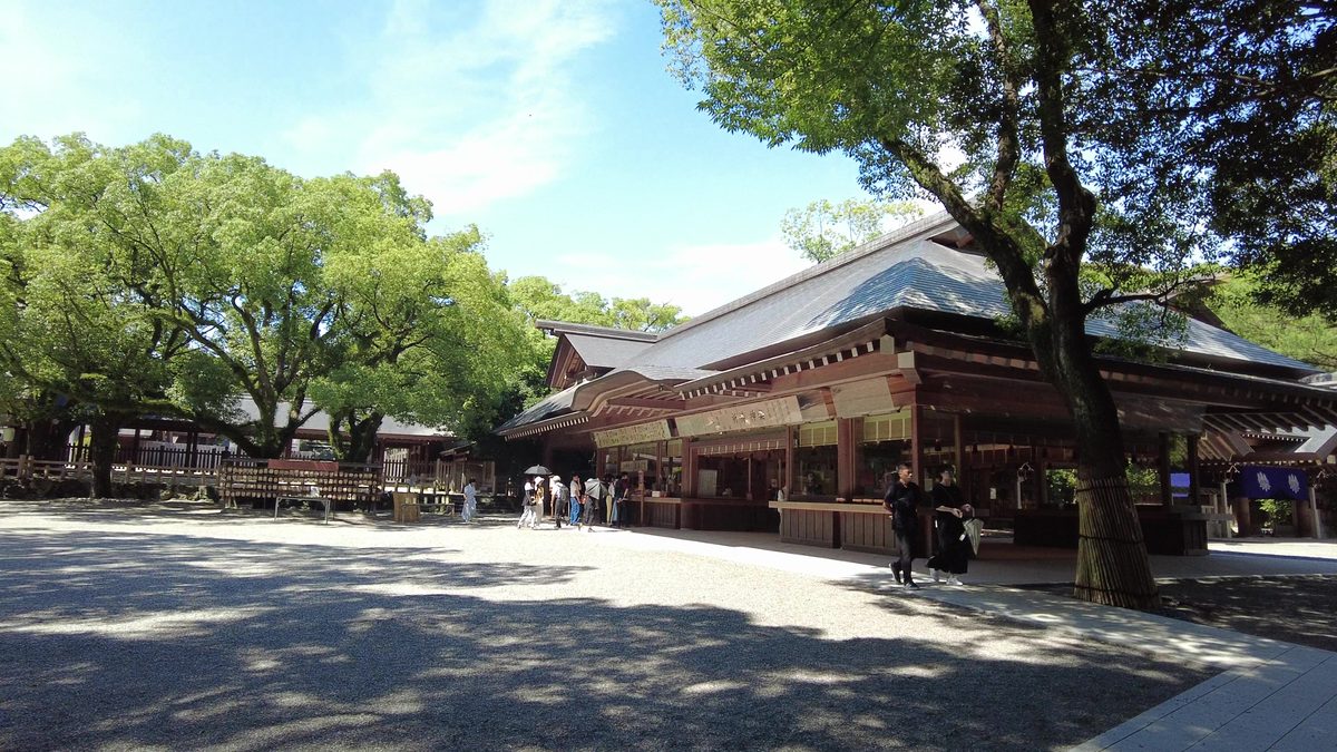 The main sanctuary's grand cypress-bark roof rising above the gravel courtyard, framed by tall trees.