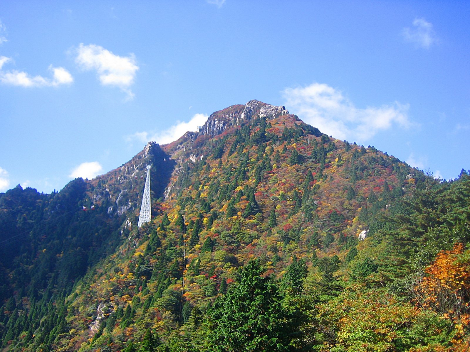 Mt Gozaisho rising into a blue sky, with the ropeway's slender white tower standing partway up the slope.