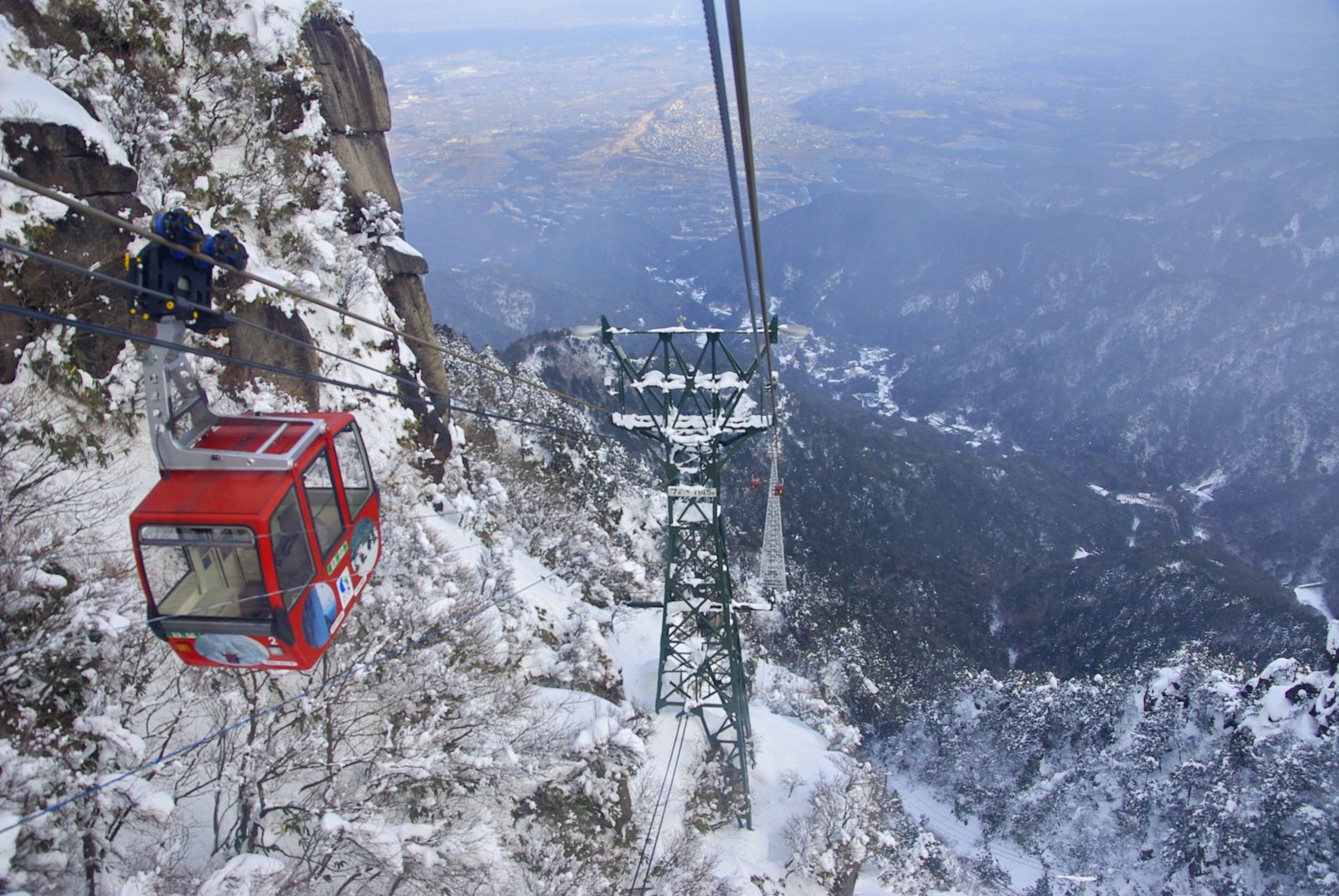 A red cabin descending past the white tower, the Nobi plain spread out far below. In winter the summit turns to frost-covered trees, and the ropeway runs all year round.