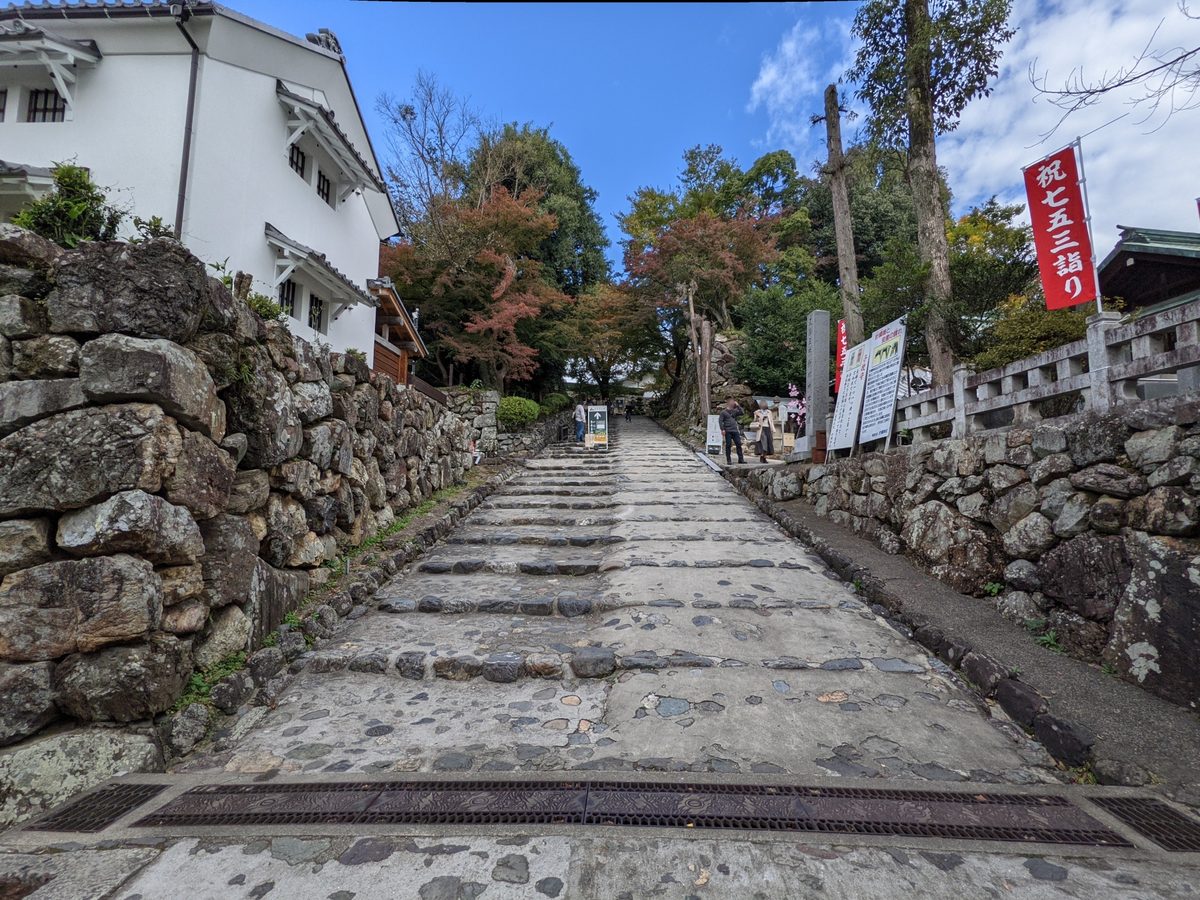 The old stone-paved approach climbing between white-walled buildings and weathered stone retaining walls.
