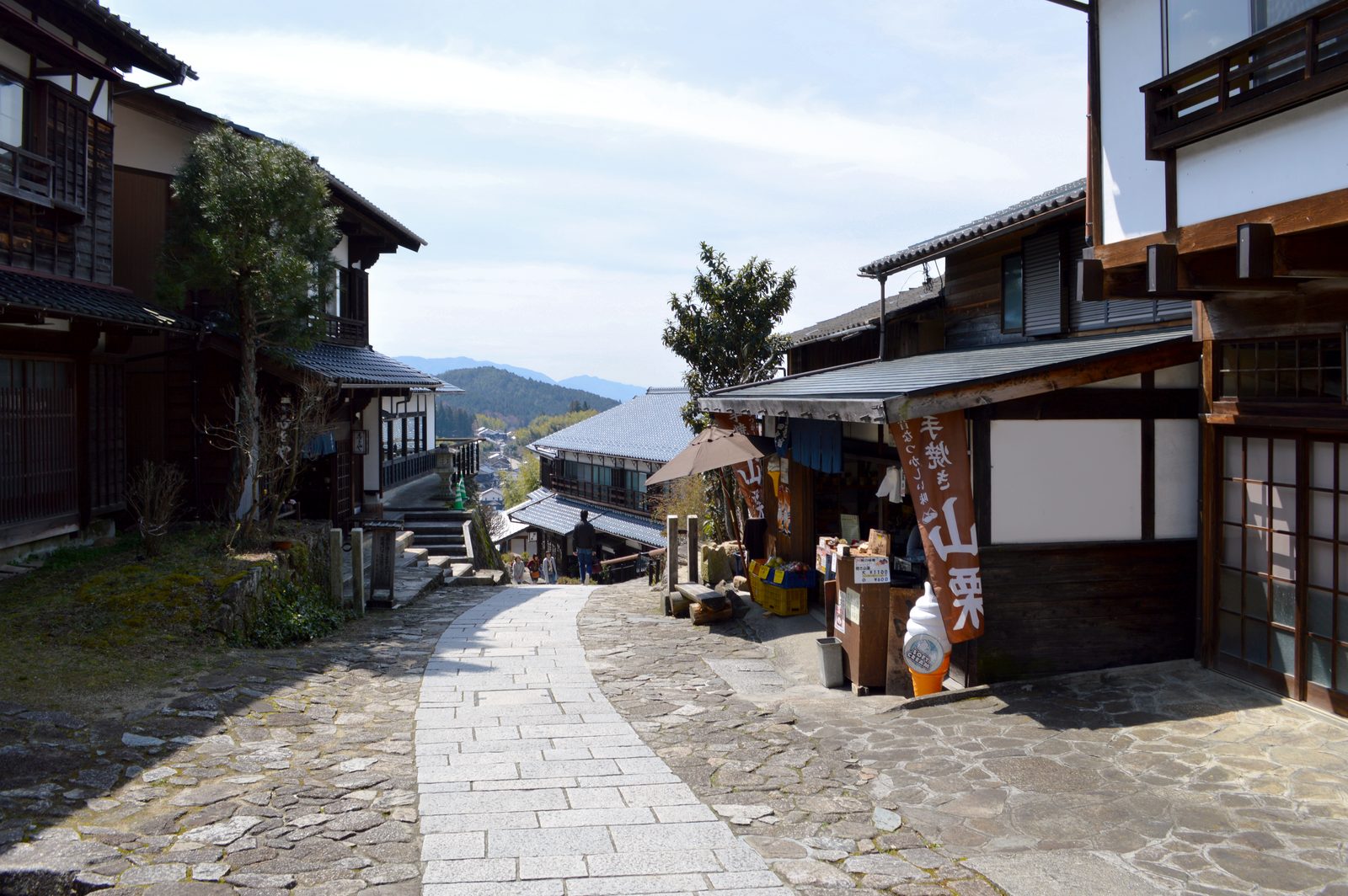 A steep stone-paved street climbing the hillside at Magome, lined with dark wooden inns and shopfronts