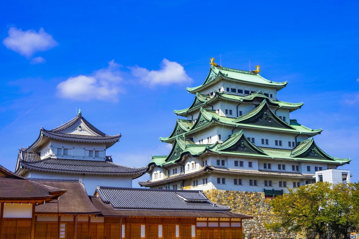 The great keep with green-tiled roofs and golden shachihoko gleaming against a blue sky.
