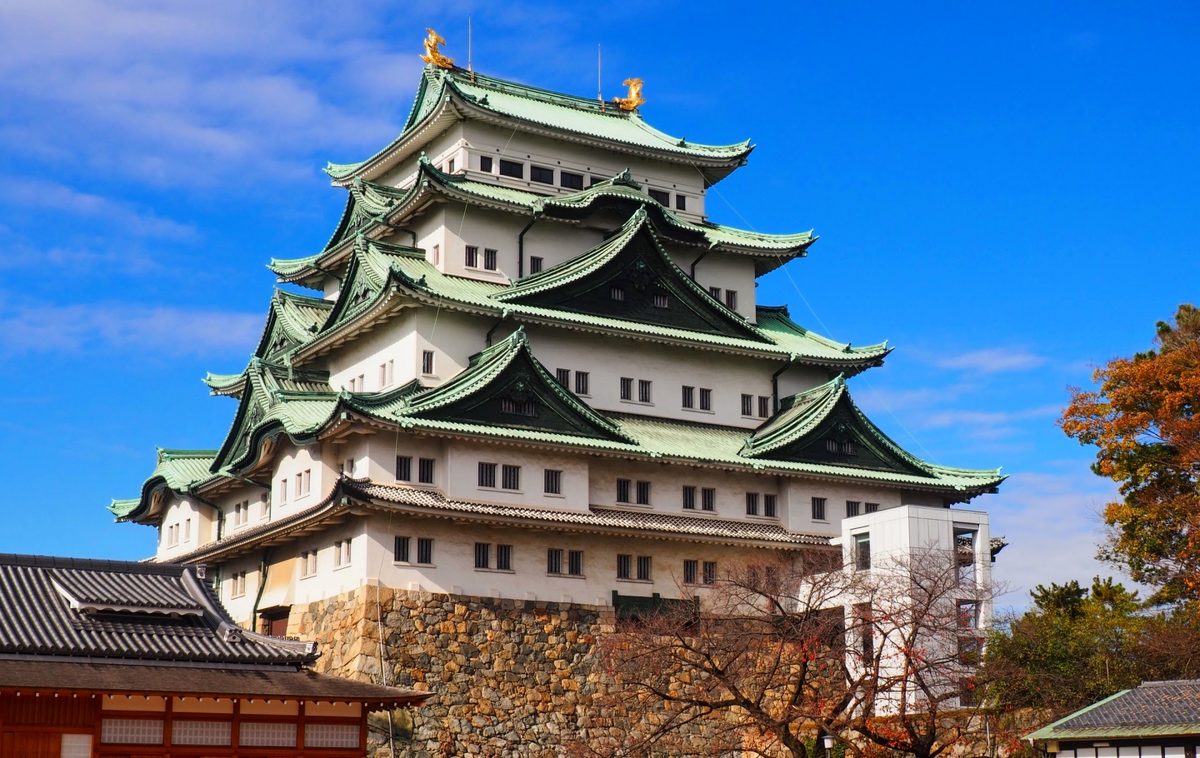 Close-up of the tiered castle keep, golden shachihoko crowning its rooftop above stone walls.