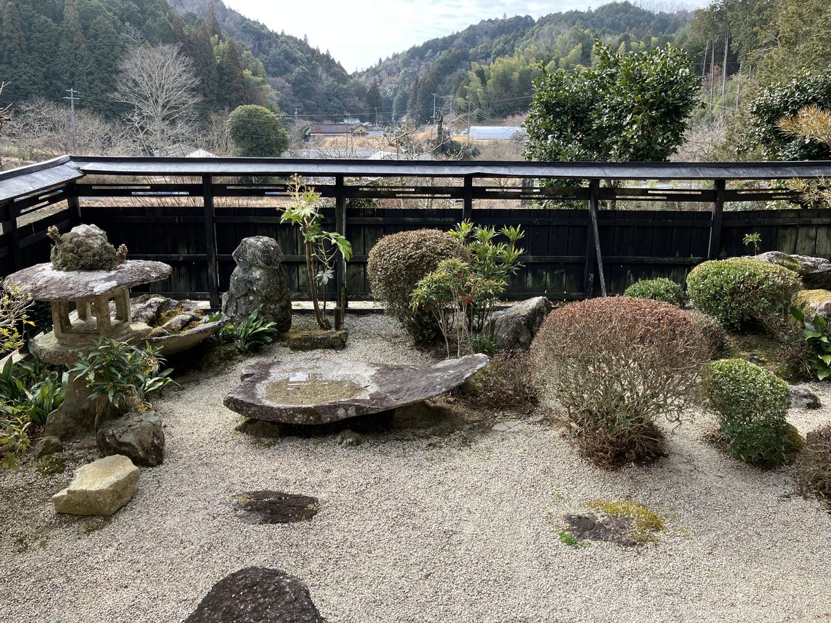 The atelier garden, with a stone lantern and clipped shrubs facing the hills.