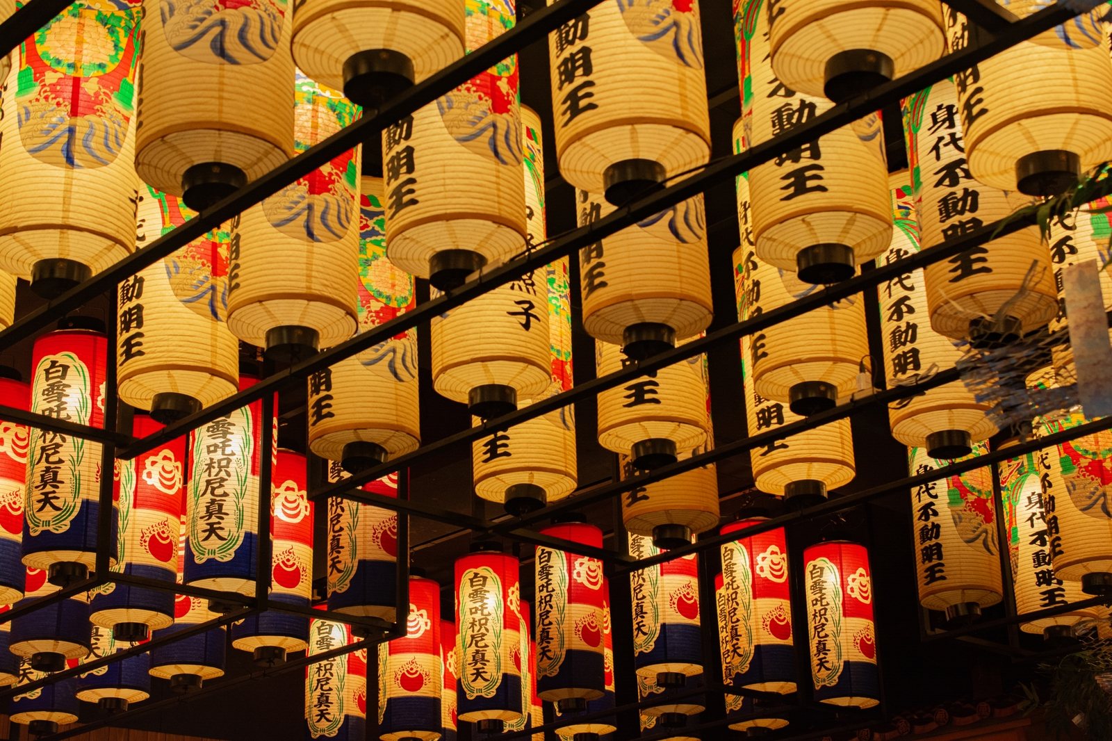 Paper lanterns glowing at dusk, warm light spilling over the temple grounds and lanes.