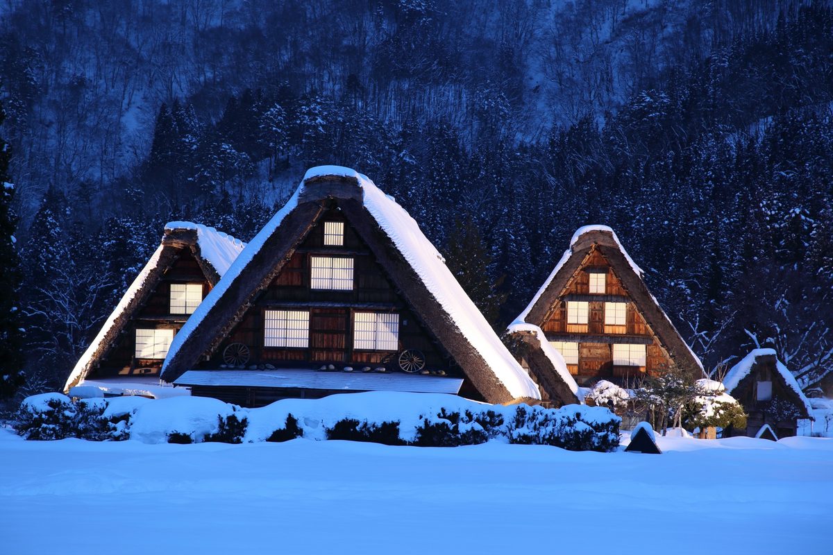 Snow-capped gassho-zukuri farmhouses glowing at dusk in winter
