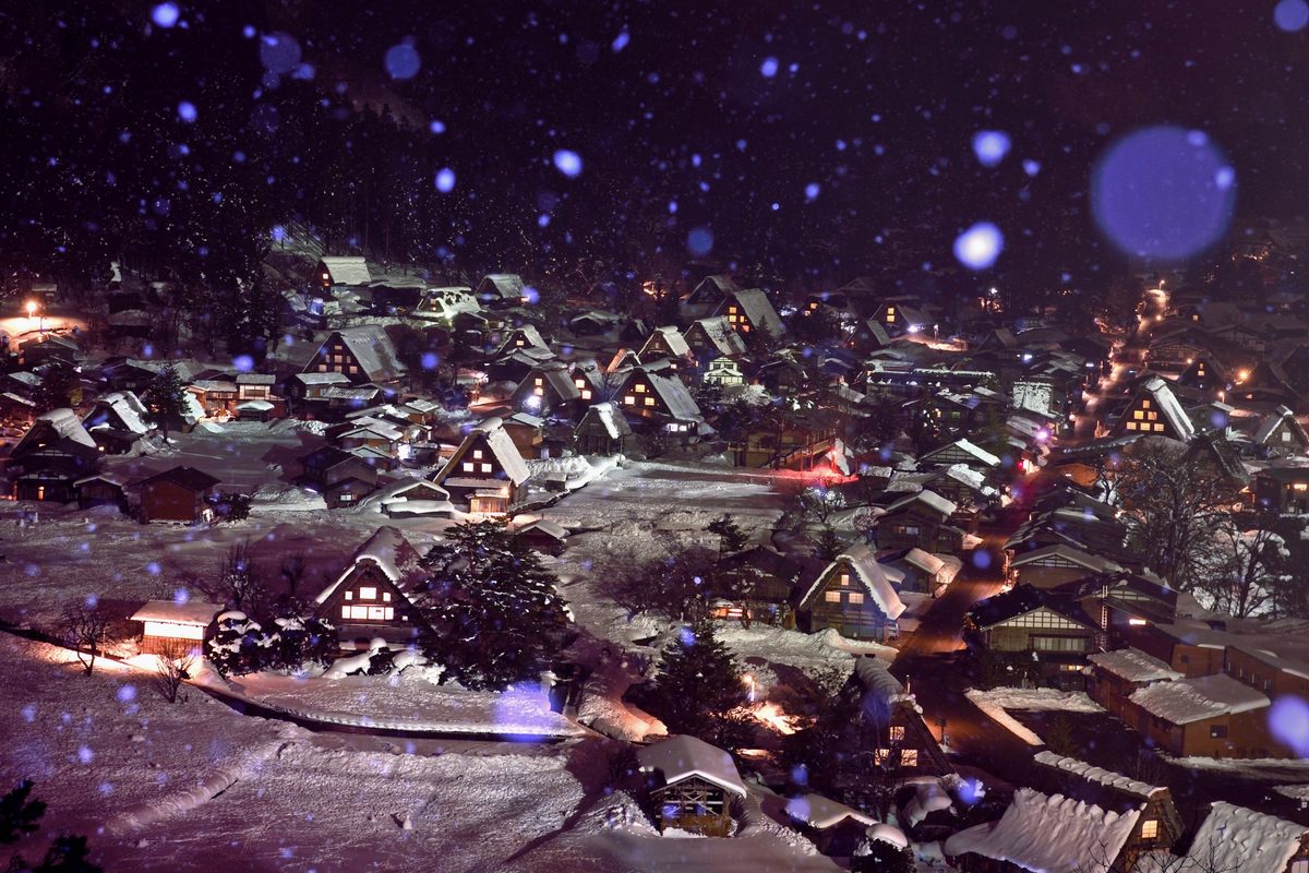 The village at night during snowfall, windows softly lit
