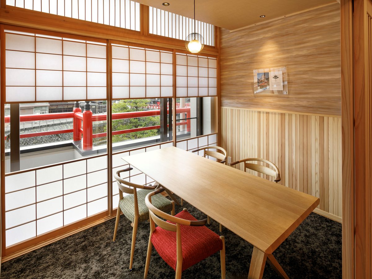 A wood-panelled dining room overlooking a red bridge through the window