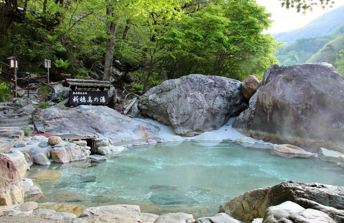 An open-air mountain hot spring among rocks and green forest
