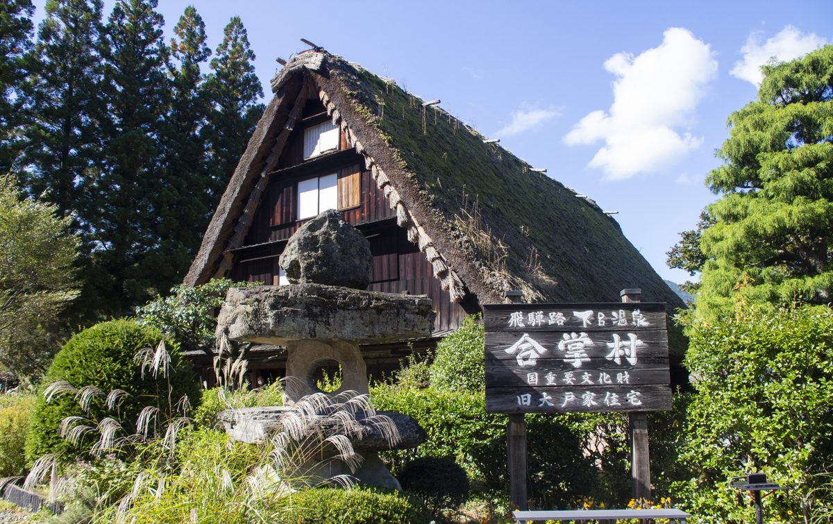 A thatched gassho-style farmhouse set against the blue sky