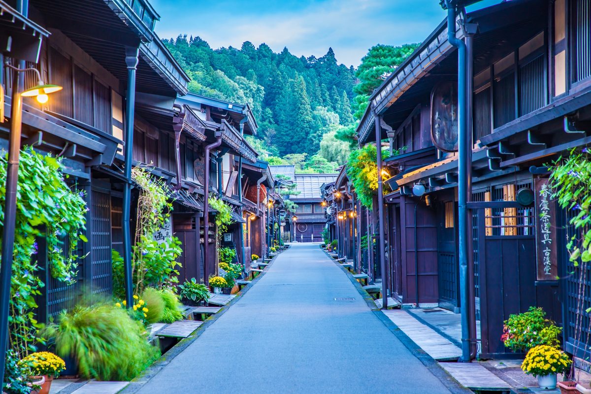 A dark-timbered Sanmachi lane lit by lanterns at first light