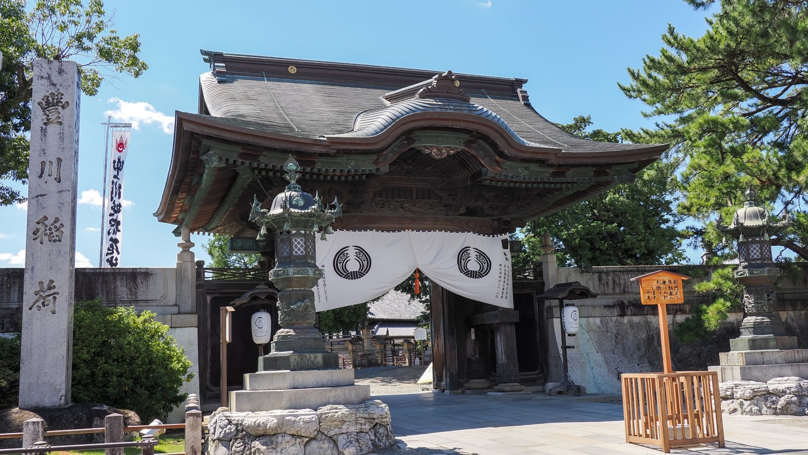 The outer gate and the stone pillar bearing the name of Toyokawa Inari, on the approach to the temple.